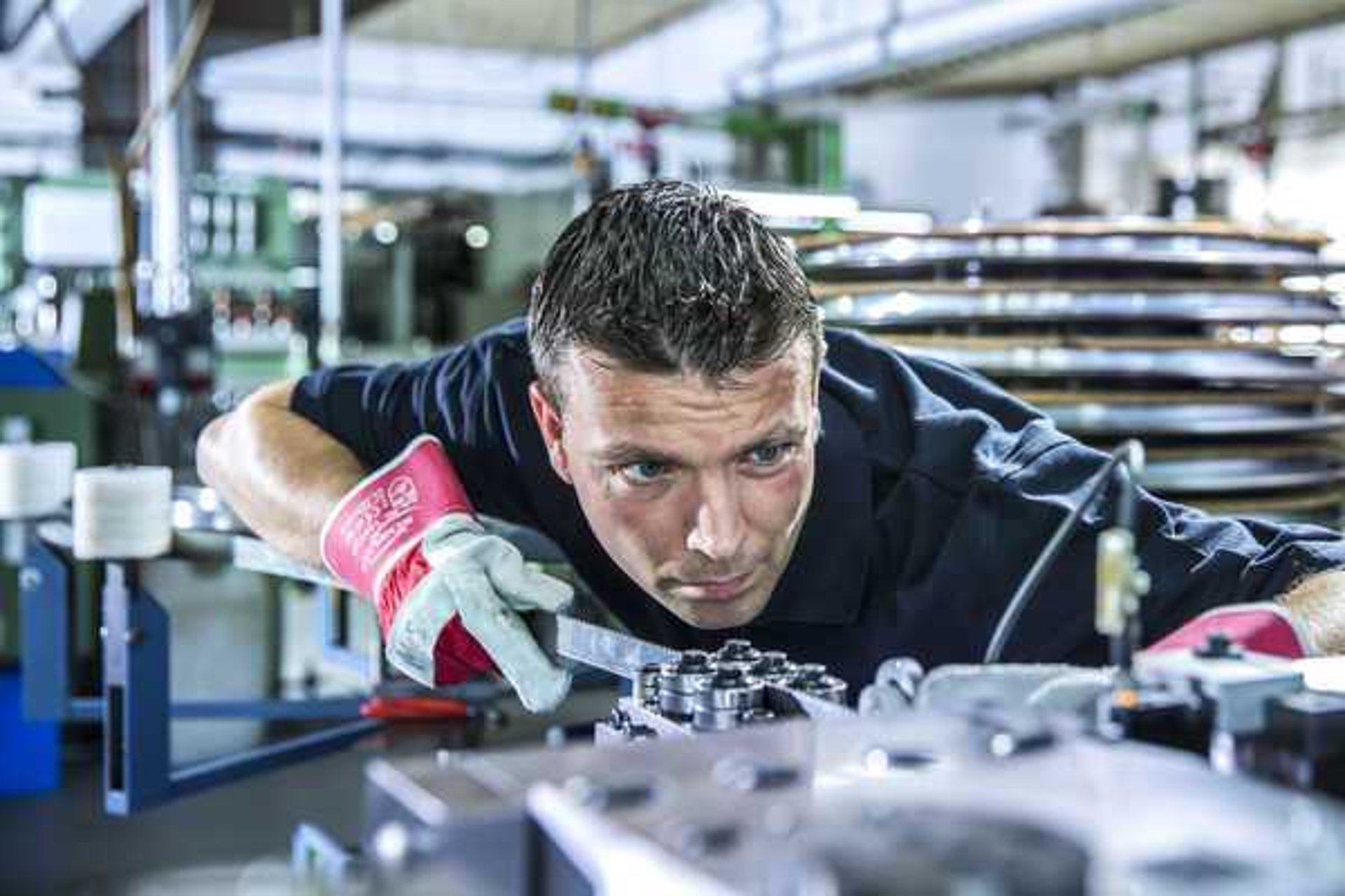Mann arbeitet an einem Sägeblatt in Produktionshalle. Ein Mann arbeitet an einem Sägeblatt in einer Produktionshalle.